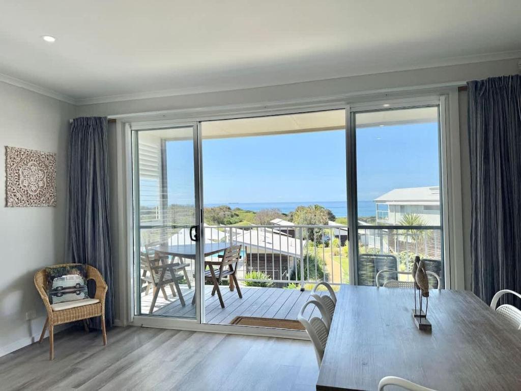 a living room with a dining table and a balcony at Ocean Mist at Caves Beach Villas in Caves Beach