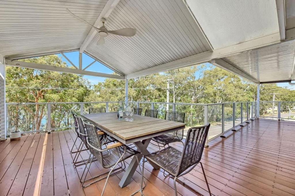 a wooden table and chairs on a deck at Upper Deck On Dobell in Wangi Wangi