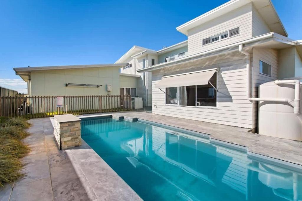 a swimming pool in front of a house at Sea Sand and Serenity at Stockton - Stunning Sophistication in Stockton