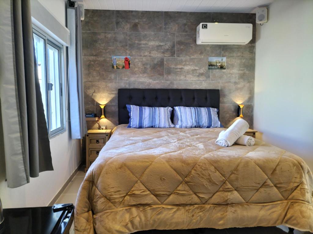 a bedroom with a large bed and a brick wall at Toscana Apartamentos in Progreso