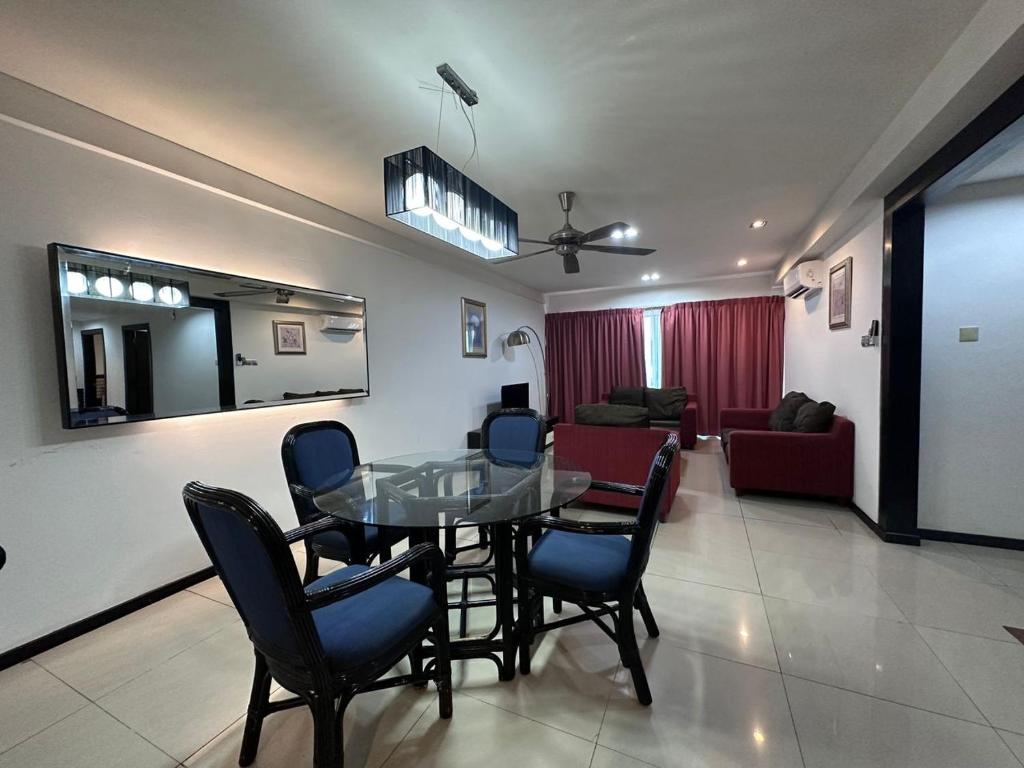 a dining room and living room with a glass table and chairs at Likas Square - KK Spacious Homestay in Kota Kinabalu