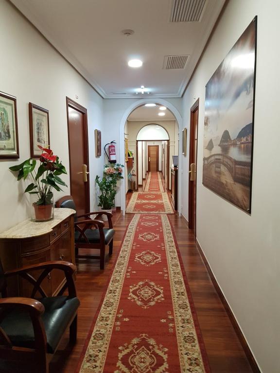 a hallway with a rug on the floor and chairs and a table and a hallway at Pension Alameda in San Sebastián