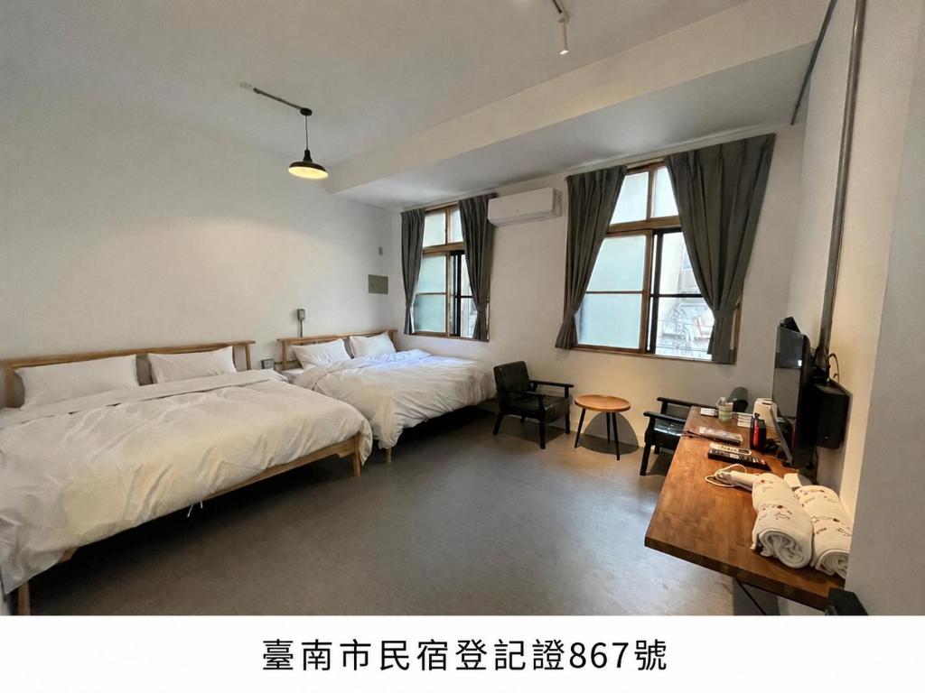 a bedroom with two beds and a table and chairs at Rolling Pin Homestay in Tainan