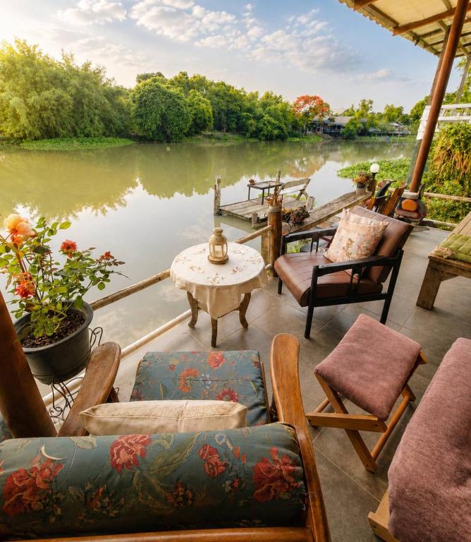 a patio with chairs and a table next to a body of water at The Scarecrow House in Ban Doem Bang (1)