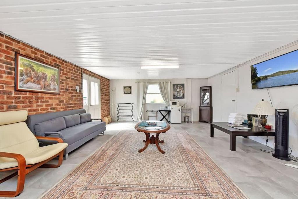 a living room with a blue couch and a brick wall at Noble Willow Studio Lovedale. A Cosy Unique Wine Country Refuge in Lovedale