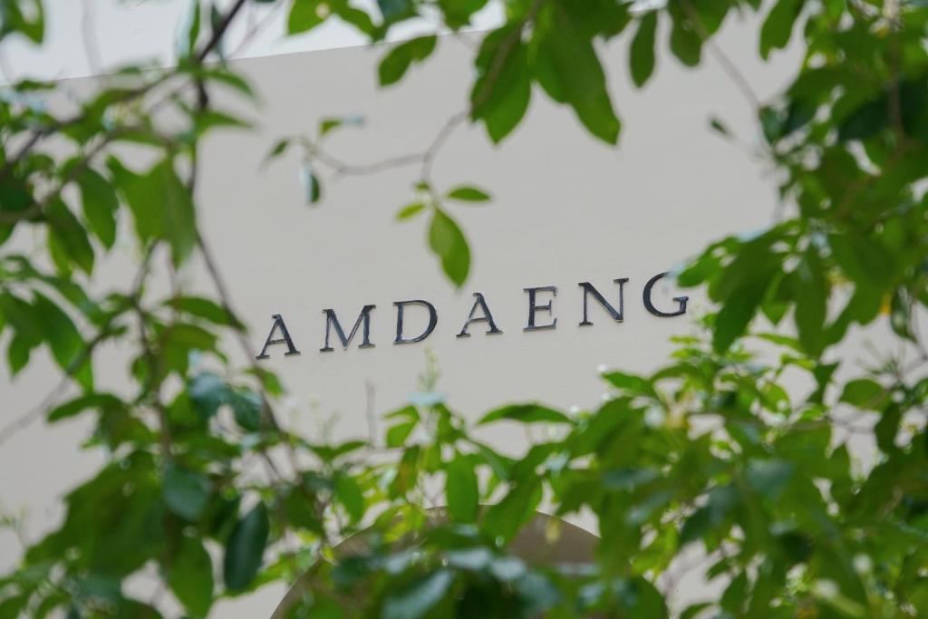 a sign obscured by trees with the words awakening at Amdaeng Bangkok Riverside Hotel in Bangkok