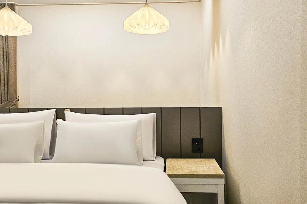 a bedroom with two beds with white pillows at 주노 호텔 in Tujŏng-dong