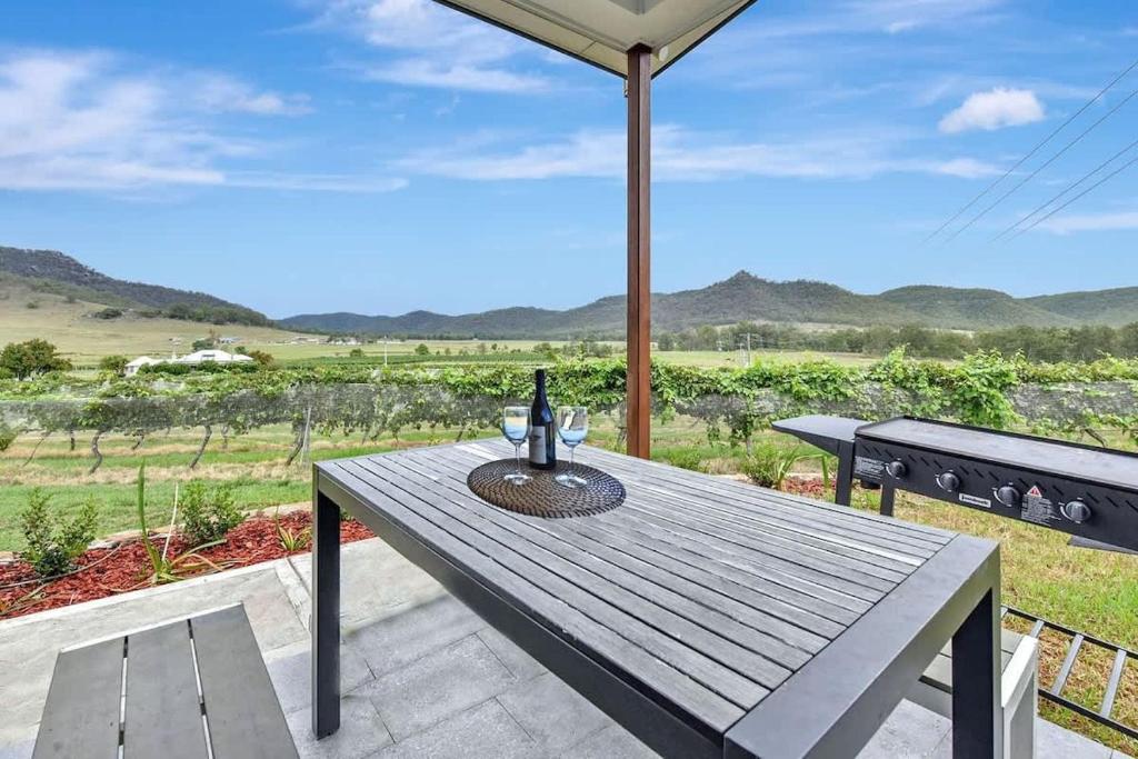 a wooden table with a bottle of wine on a patio at Somerville Wines Lux Escape 3-Bedroom Cottage Near Broke Wineries in Broke