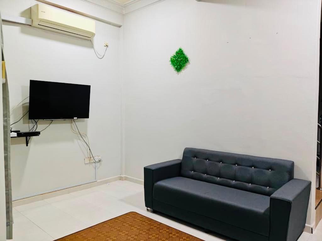 a living room with a black couch and a tv at Chendering Beach Stay in Kuala Terengganu