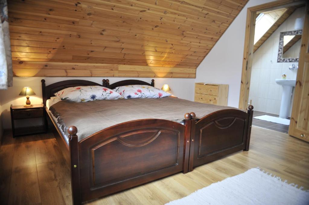 a wooden bed in a room with a wooden ceiling at "Pod Szumiącą Topolą" in Białowieża