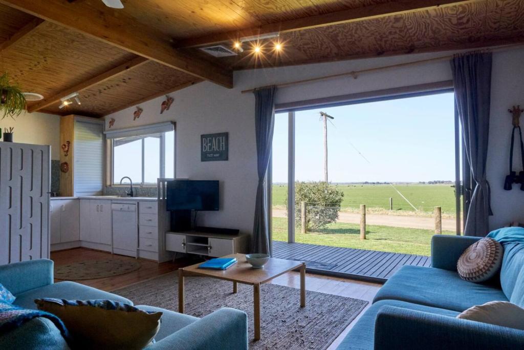 a living room with a blue couch and a large window at Far View - Pets, Linen, Wi-Fi, Netflix, Caravan, EV in Venus Bay
