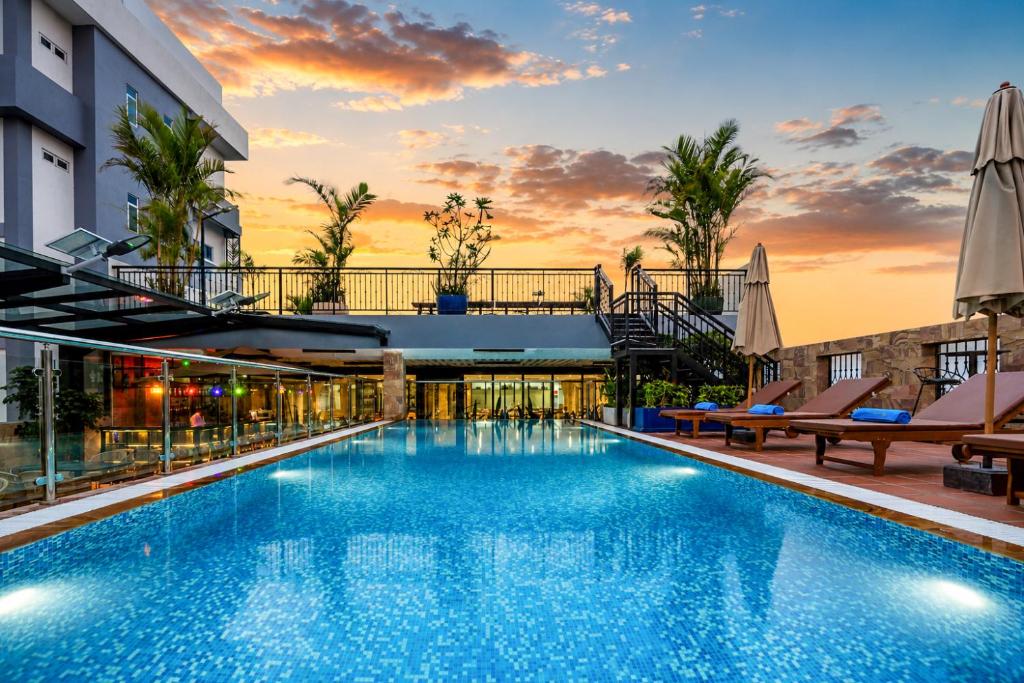 a swimming pool with chairs and a building at Amana Hotel Phnom Penh in Phnom Penh