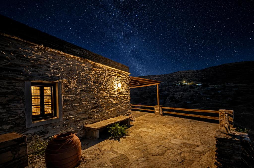 a stone building with a bench on a patio at night at Nostos Kea in Káto Meriá