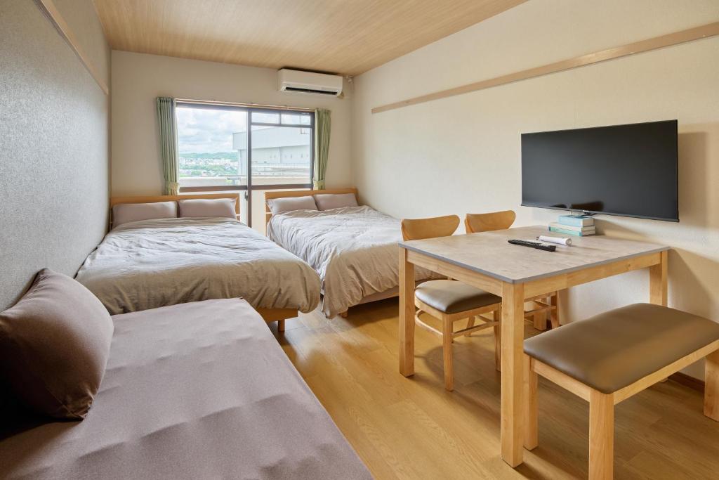 a room with two beds and a table with a television at Green hills 102 in Kumamoto
