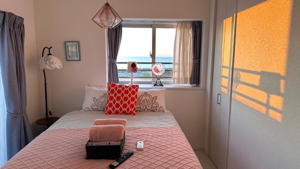 ein Schlafzimmer mit einem Bett mit einer rosa Decke und einem Fenster in der Unterkunft SunSea Okinawa Stunning Ocean View 2BR Sleeps 6 20 min from Airport 3 min to Shopping Mall in Urazoe