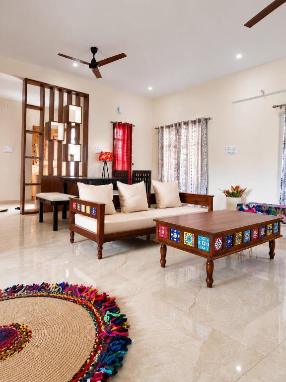a living room with a couch and a table at Holapu Thayi Villa in Mysore