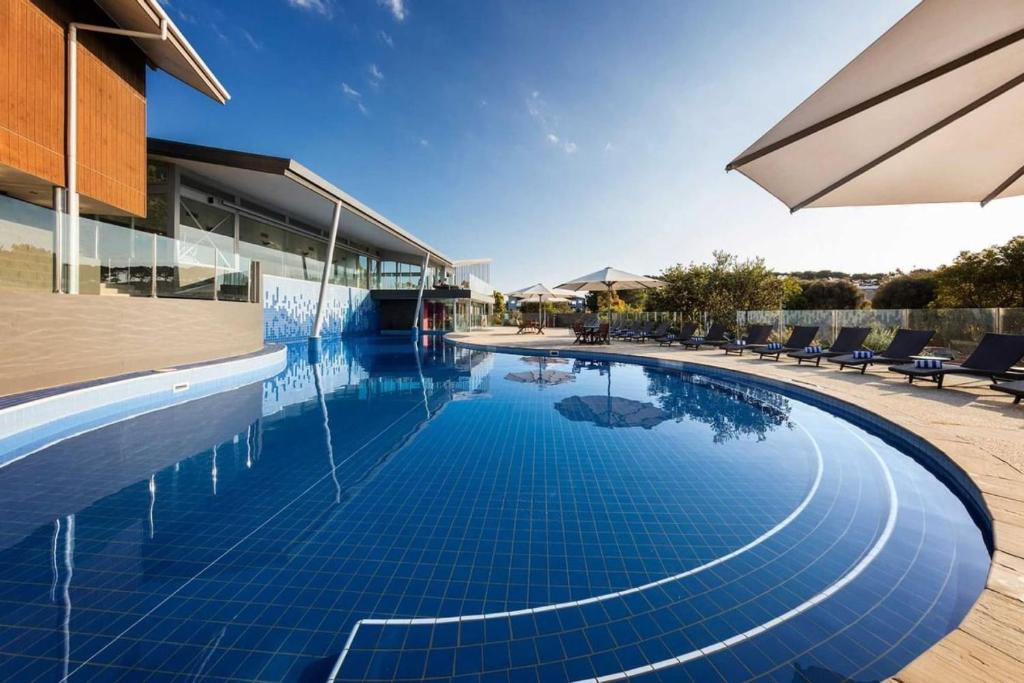 a swimming pool with a blue tile floor and a building at Potters Hill Haven in San Remo