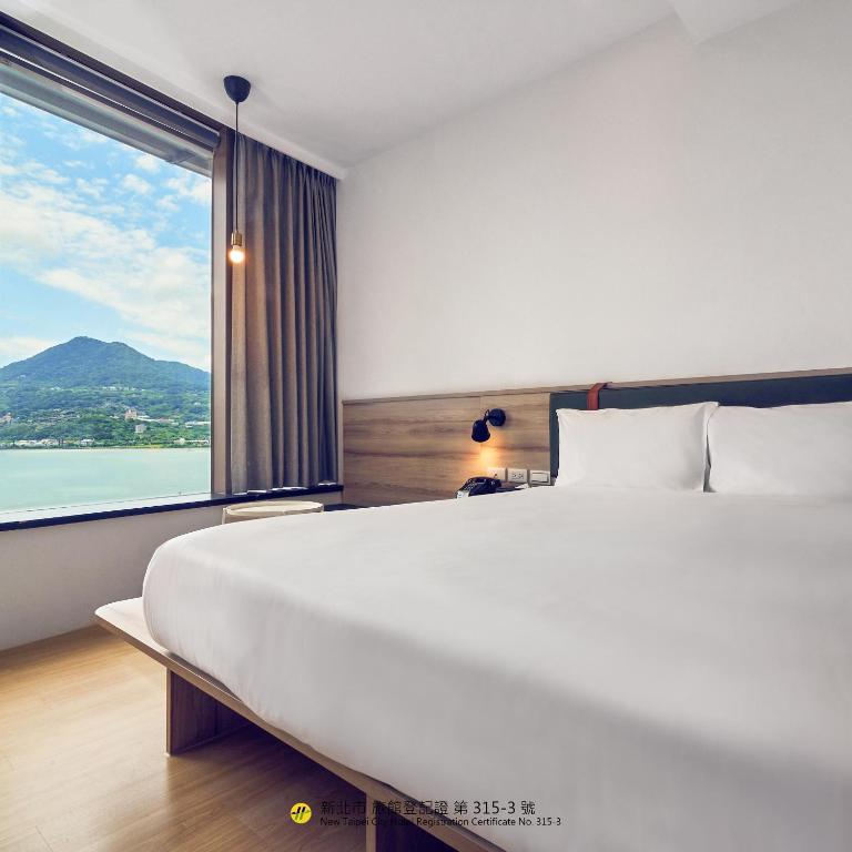 a bedroom with a large bed and a large window at CHECK Inn Express New Taipei Tamsui in Tamsui