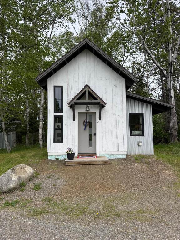 a small white house with a door in a yard at The Alpine Suite | Walk to Downtown & Rangeley Lake Beach in Rangeley