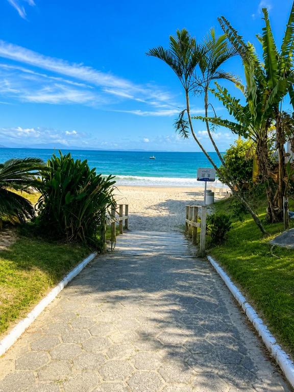 a path to the beach with a palm tree and the ocean at Casa Da Praia Apart Hotel in Florianópolis