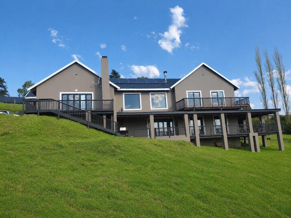 a large house on top of a grassy hill at Underwood Country Manor in Underberg