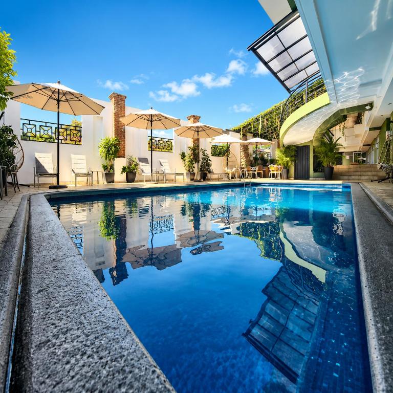 a swimming pool with umbrellas in a building at Hotel Borda Cuernavaca in Cuernavaca