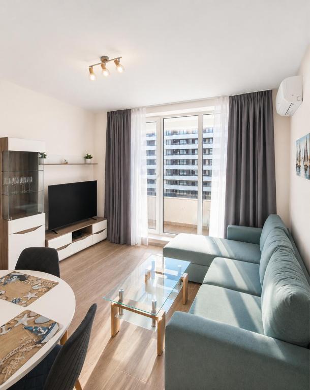 a living room with a blue couch and a table at Pool View Apartment Varna in Varna City