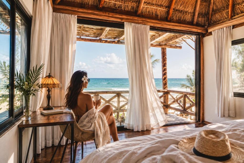 a woman sitting at a desk in a room with a view of the ocean at Olivia Oceanfront Tulum in Tulum