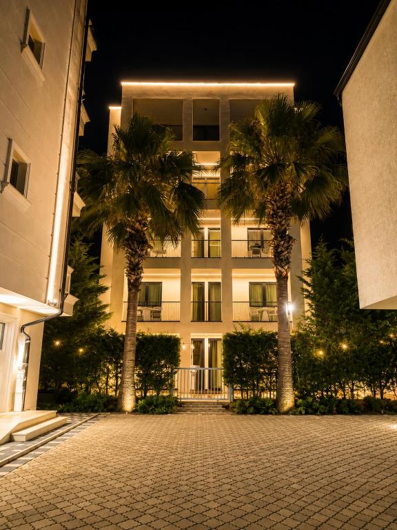 two palm trees in front of a building at night at Bedo Boutique Hotel in Golem