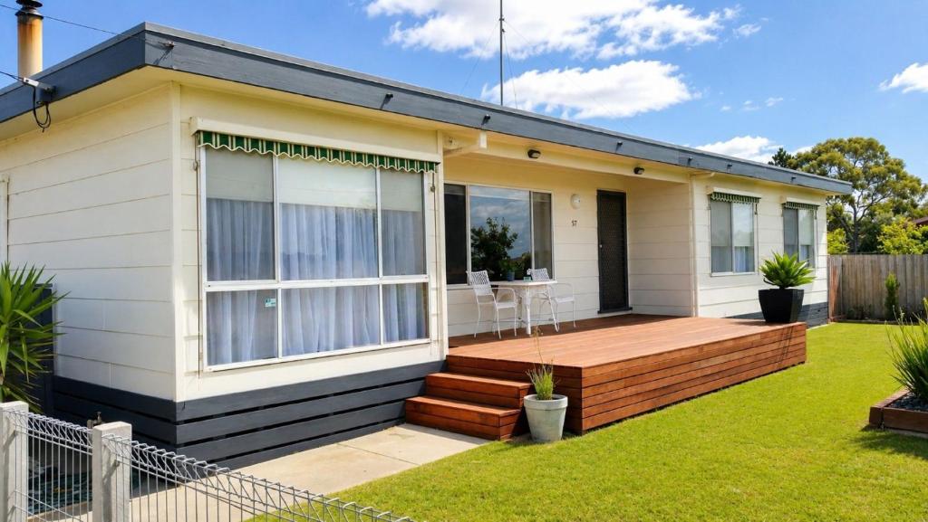 a house with a wooden deck in the yard at Coastal Cottage in Saint Leonards