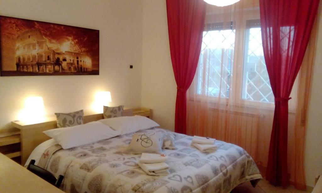 een slaapkamer met een bed met rode gordijnen en een raam bij B&B Salviani in Acilia