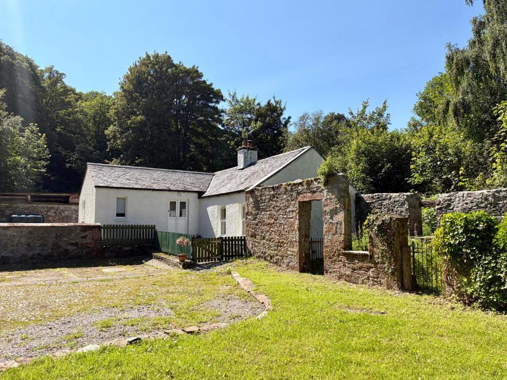 an old stone house with a gate in a yard at Laundry Cottage in Strathpeffer