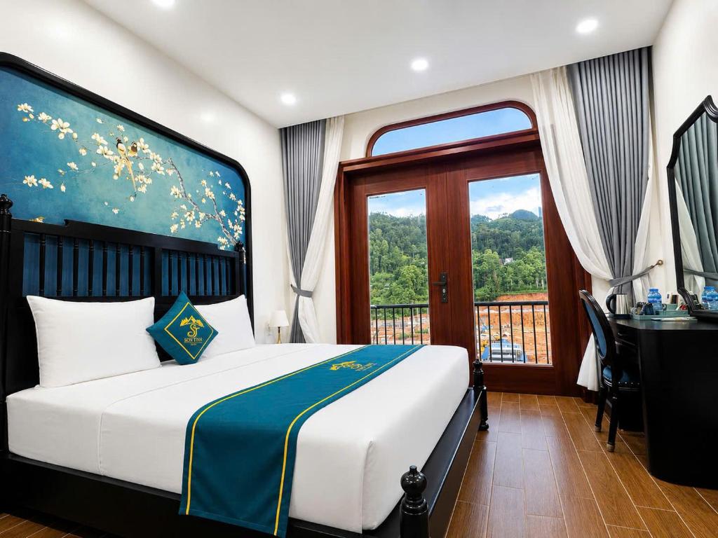 a bedroom with a bed and a desk and a window at Son Tinh Hotel in Dồng Văn