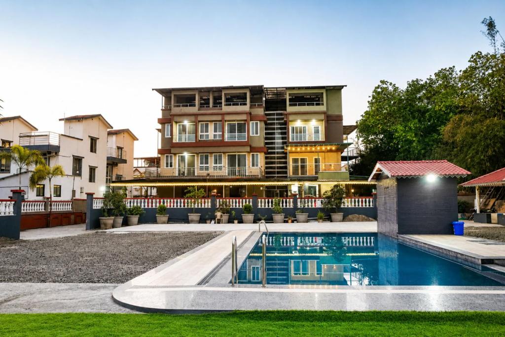 a house with a swimming pool in front of a building at The Tree Resort in Malavli