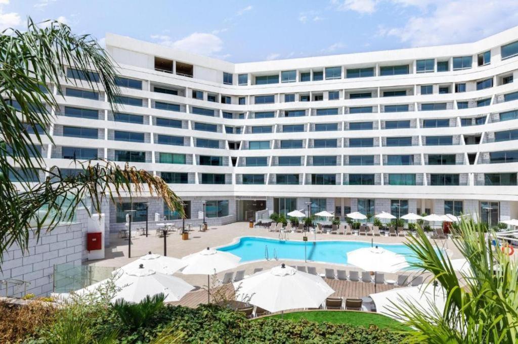 a large white building with a pool and umbrellas at סי סייד אילת חדר משפחתי מפנק עם נוף לים in Eilat