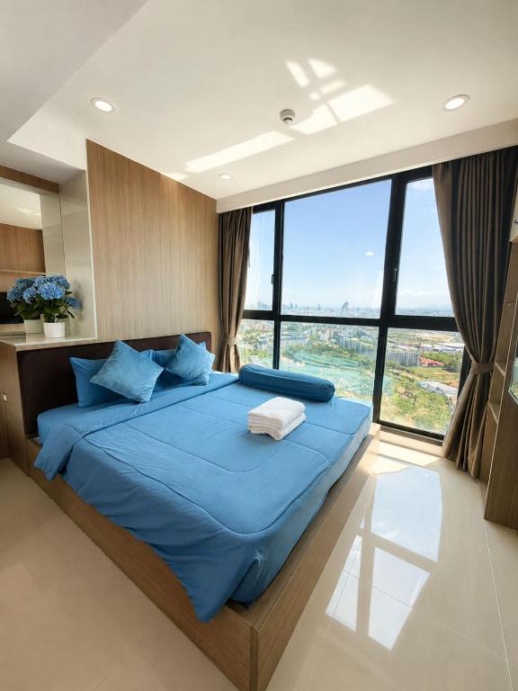 a bedroom with a blue bed with a large window at Sea View Room - Infinity Pool near Terminal 21 in Pattaya