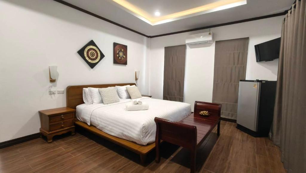 a bedroom with a bed and a table and a television at Ladda Garden Home in Klong Muang Beach