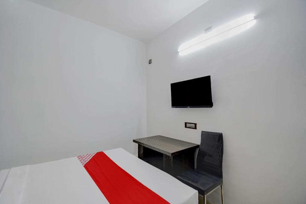 a room with a bed and a table and a tv at Hotel O ALISHA LODGE in Āsansol