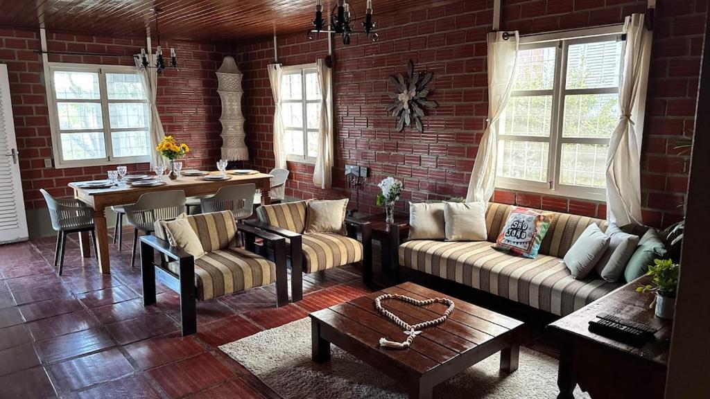 a living room with couches and a table and a brick wall at Casa da Paz - Gravatá in Gravatá