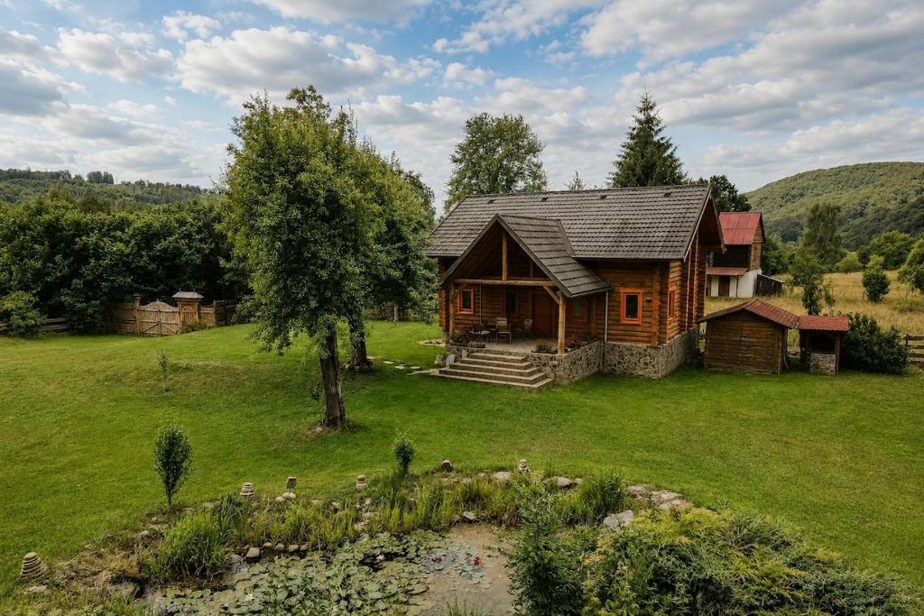 a log cabin in the middle of a field at Traditional wooden cottage in Cîmpu Cetăţii