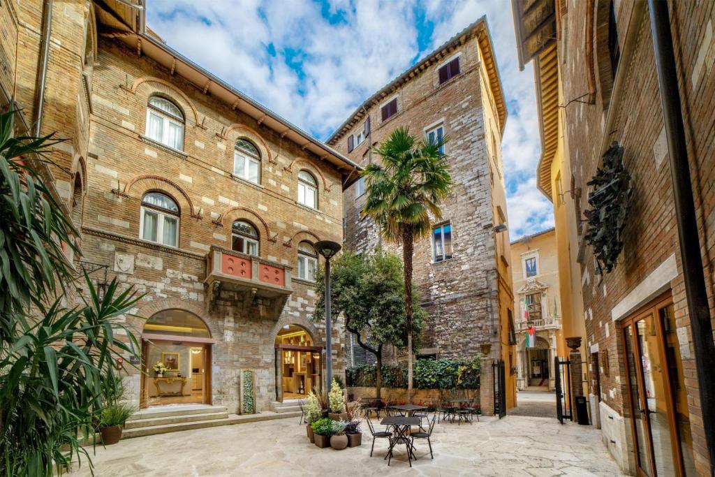 an alley in an old building with a palm tree at Rosetta Hotel Perugia Tapestry Collection By Hilton in Perugia
