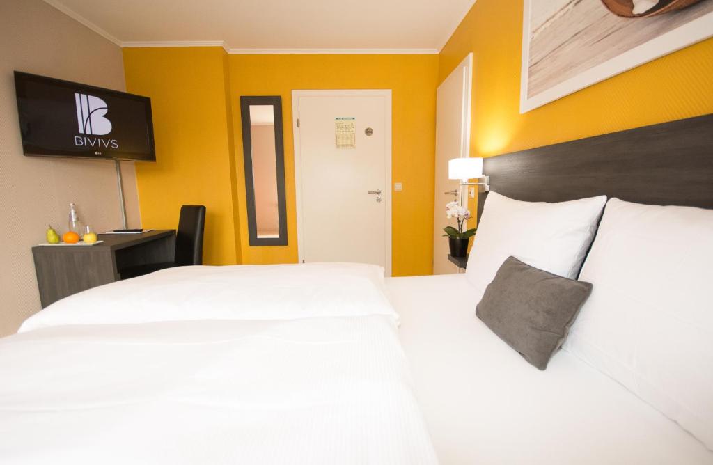 a bedroom with two white beds and yellow walls at BIVIUS Hotel Restaurant Luxembourg in Luxembourg