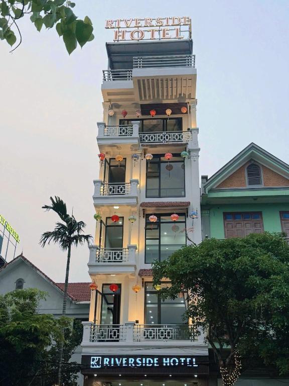a tall building with a sign on top of it at Riverside Hotel in Kỳ Vĩ