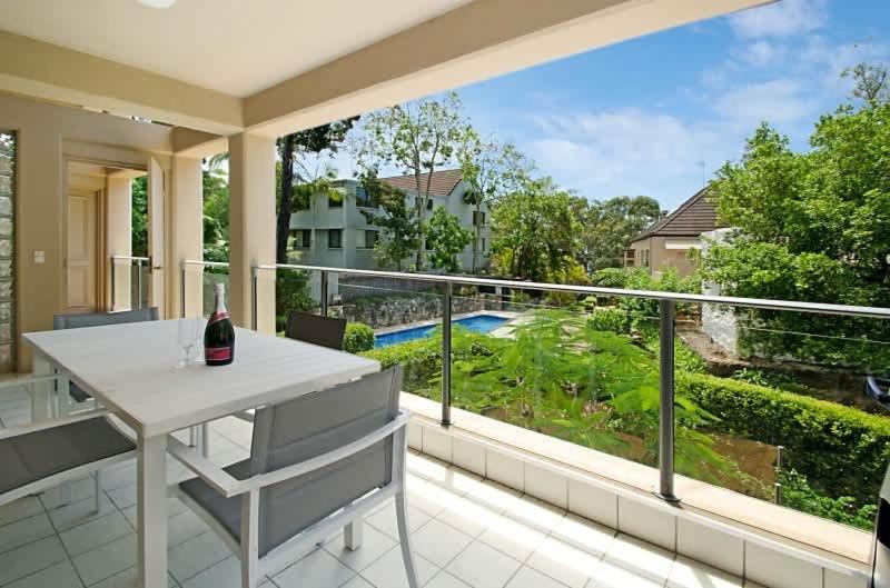 a balcony with a white table and a view of a yard at Alderly Terrace in Noosa Heads