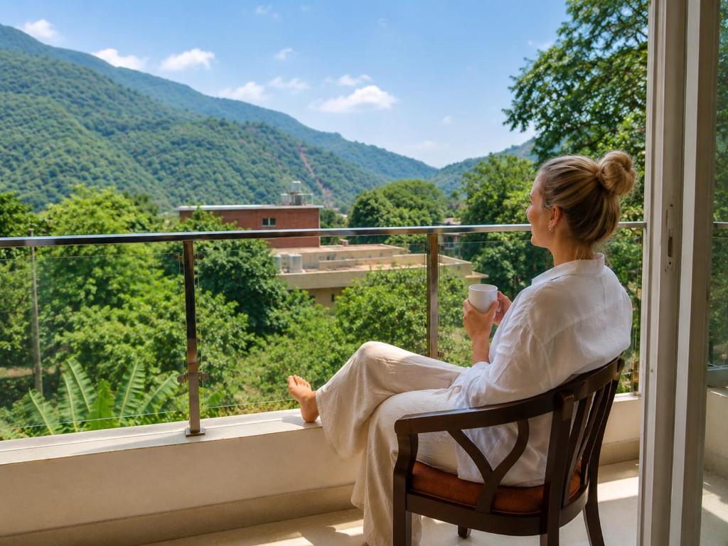 a woman sitting on a balcony with a cup of coffee at Mountain View Retreat in Yog Tapovan in Rishīkesh