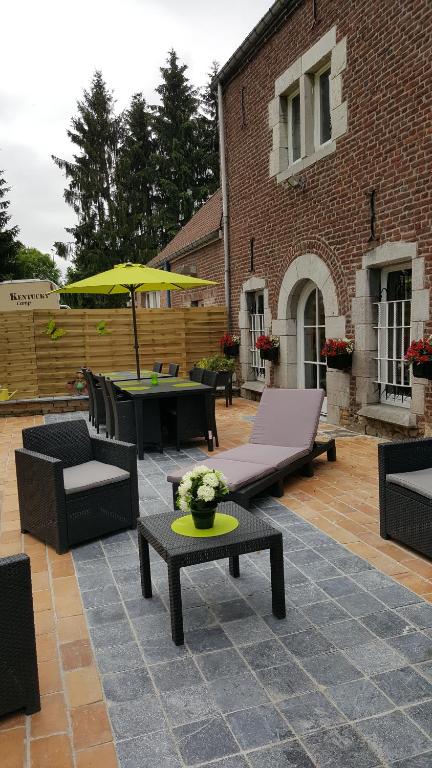 d'une terrasse avec des tables, des chaises et un parasol jaune. dans l'établissement le gite de zoelie, à Chaineux