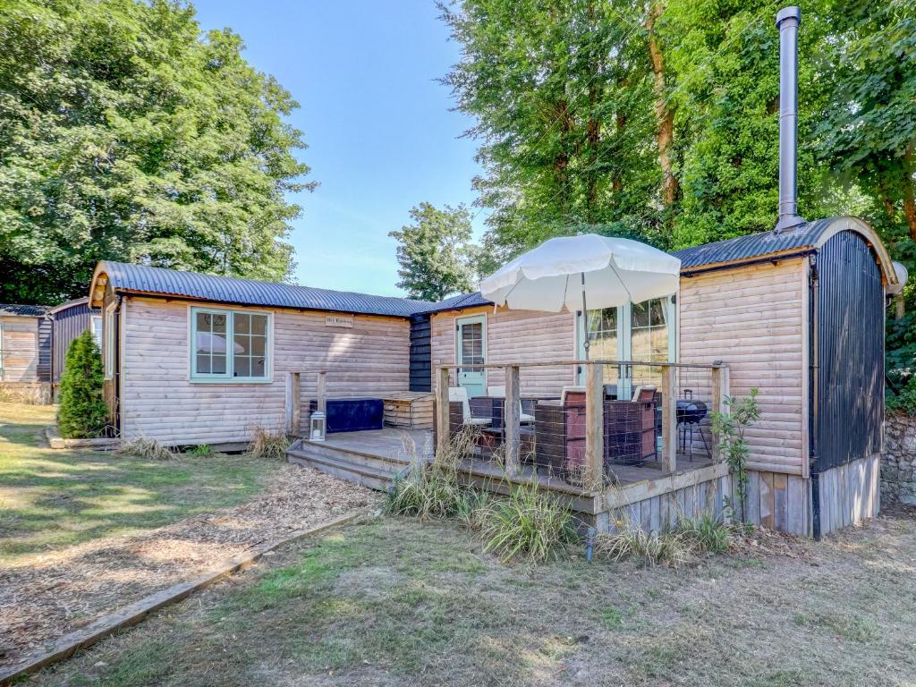 a wooden house with an umbrella in the yard at Hoy Hideaway in Whitwell