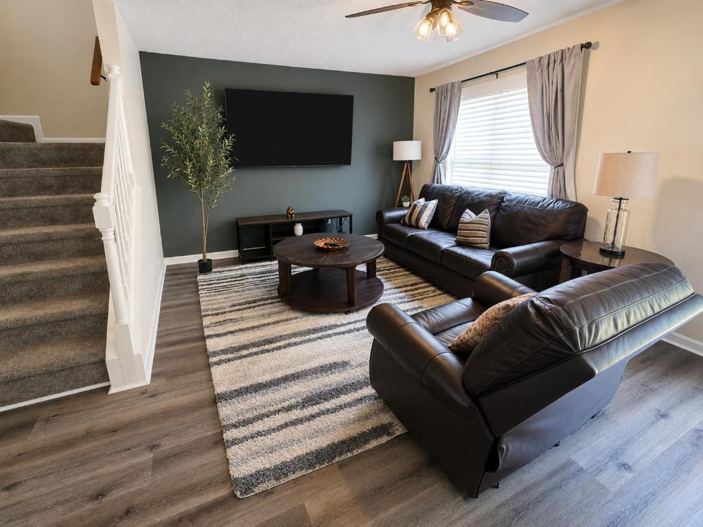 a living room with a leather couch and a television at Spacious 3BR Retreat Perfect for Groups Near Downtown in Raleigh
