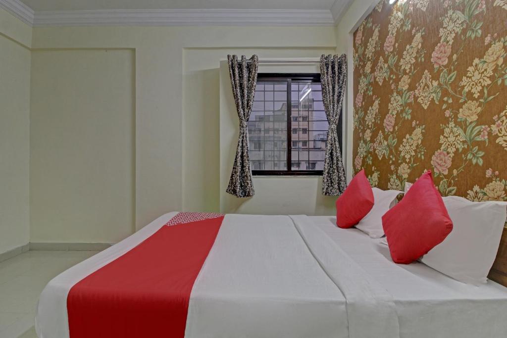 a bedroom with a large bed with red and white pillows at Hotel O Sai Executive Lodging in Māngvādi