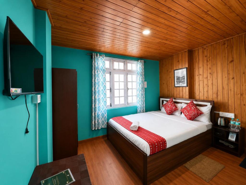 a bedroom with a bed and a tv in a room at Hotel Pinecrest Inn Darjeeling With Mountain View Room And Parking - Restaurant Facility in Darjeeling